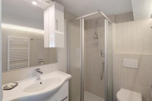 a white bathroom with a sink and a shower at Pension Waldheim Rooms in San Giacomo