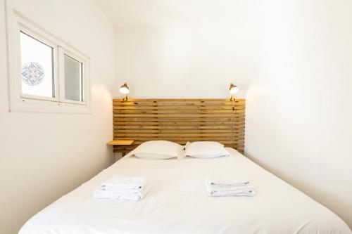 a bedroom with a bed with two towels on it at La Cabane in Combrit