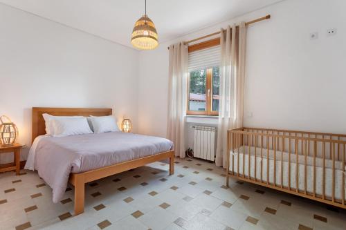 a bedroom with a bed and a crib and a window at Quinta Vale do Tejo in Chamusca