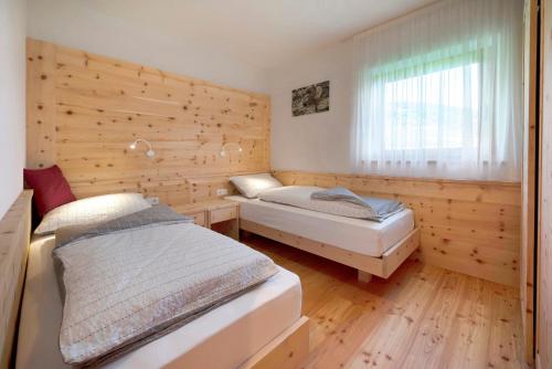 a bedroom with two beds and a window at Teutenhofer Zwetschge in Feldthurns