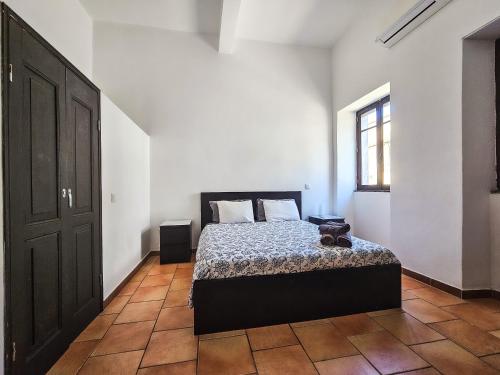 a bedroom with a bed and a window and a door at Casa na Vila T2 in Fuzeta