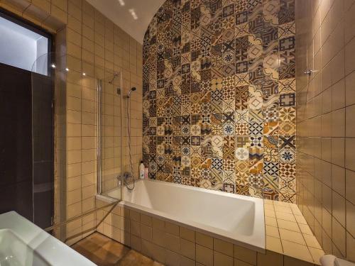 a bathroom with a tub and a mosaic tile wall at Casa na Vila T2 in Fuzeta