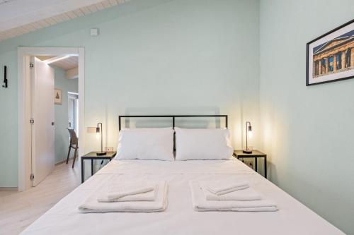 a white bedroom with a large white bed with two tables at Residenza Borgo Antico Lucia in Ascea