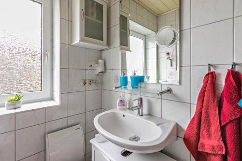 a white bathroom with a sink and a mirror at Ferienhaus Ongi in Friedrichskoog-Spitze