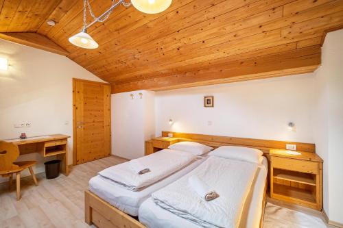 a bedroom with two beds and a wooden ceiling at Gartnerhof Apt Sonnenblume in Colle Isarco