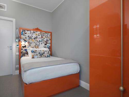 a small bedroom with a bed with an orange headboard at Anjoy&Bleev Rooms in Rho