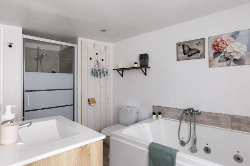 a white bathroom with a tub and a toilet at Gite Cocon et Balnéo in Selles-sur-Cher