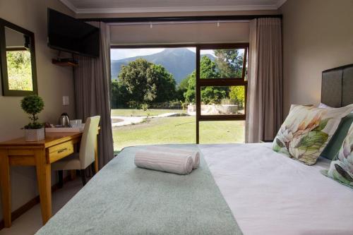 a bedroom with a bed with a desk and a window at Tsitsikamma Manor in Stormsrivier