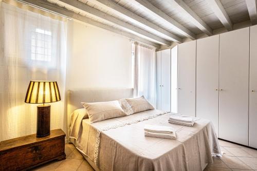 a bedroom with a bed with a lamp and a window at Nido di Cisano in San Felice del Benaco