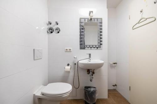 a white bathroom with a toilet and a sink at Aldars Urban Trio Suite No.6 in Munich