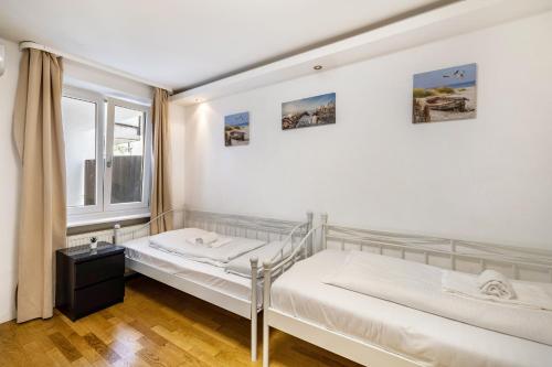two beds in a room with a window at Aldars Urban Trio Suite No.6 in Munich