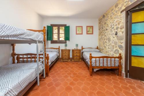 a bedroom with two bunk beds and a stone wall at Masía Can Garriga, Casa Gran in Girona