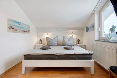 a bedroom with a white bed in a room with a window at Haus A Cappella B6 in Binz