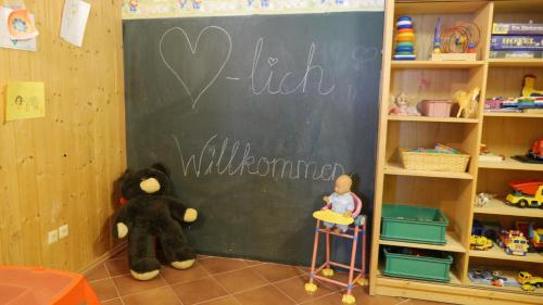 a classroom with a blackboard with a teddy bear and a child in front at Hotel Dreisonnenberg in Neuschönau