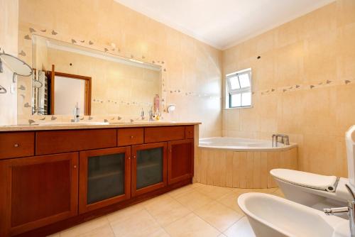 a bathroom with a tub and a toilet and a sink at Villa Delphin in Lagos