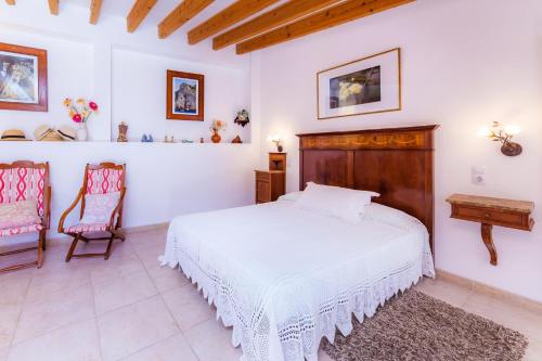 a bedroom with a white bed and two chairs at Can Murons in Fornalutx