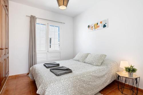 a white bedroom with a bed and a window at Casa Sabrina, Terraza Vista Mar in Playa Honda