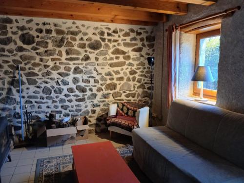 a living room with a couch and a stone wall at La Garnasette in Beaulieu