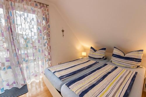 a bedroom with a bed with striped pillows and a window at Ferienwohnung Ingrid Heyes in Radolfzell am Bodensee