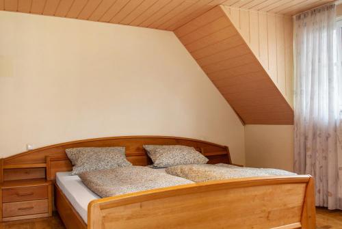 a bedroom with a wooden bed with two pillows at Ferienhaus Blumenstock in Steinsfeld
