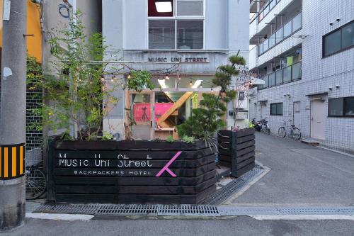 a building with a sign that reads music unpluggedaggressiveverb at Music Uni Street Backpacker's Hostel in Toyonaka