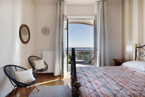 a bedroom with a bed and two chairs and a balcony at Villa Cristina - vista mare in Boissano
