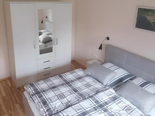 a white bedroom with a bed and a dresser at Ferienwohnung Rösner in Herzhausen