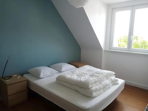 a bed with white sheets and pillows in a room with a window at Maison quartier Porzic vue Mer in Crozon
