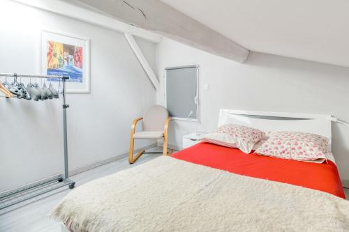 a white bedroom with a red bed and a chair at Gite Azur Toulouse Sud in Lherm
