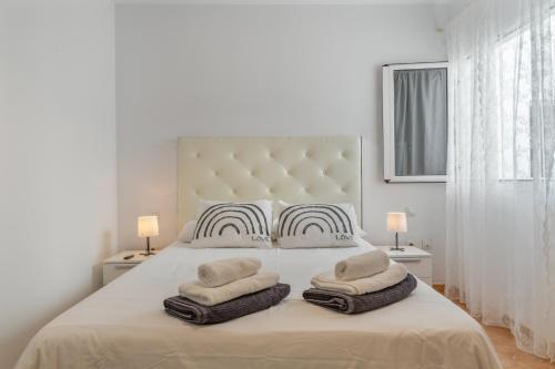 a white bedroom with a large white bed with towels on it at El Barquillo in La Santa