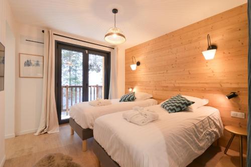 two beds in a room with wooden walls at Chalet avec Piscine La Plagne in La Plagne Tarentaise