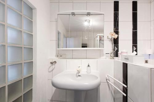a white bathroom with a sink and a mirror at Villa Black Forest in Adelhausen