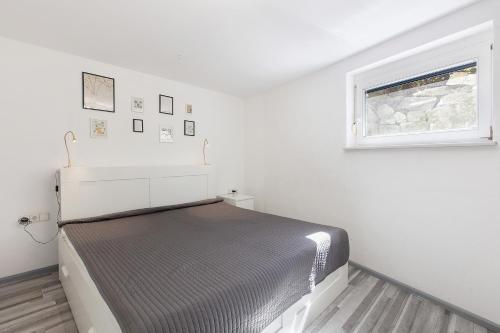 a white bedroom with a bed and a window at Villa Black Forest in Adelhausen