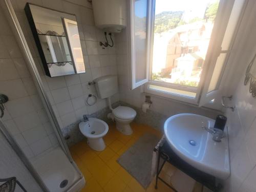 a bathroom with a toilet and a sink and a window at Garibaldi vista Giardino in Bonassola