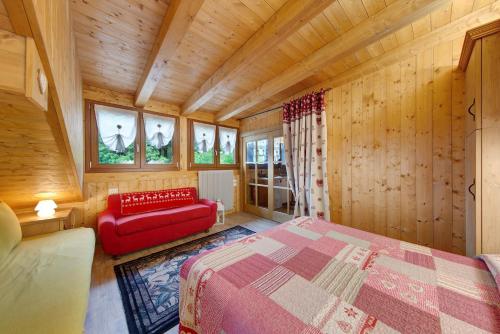 a bedroom with a bed and a red couch in a room at La Casa dei Cervi a Vinigo in Vodo Cadore