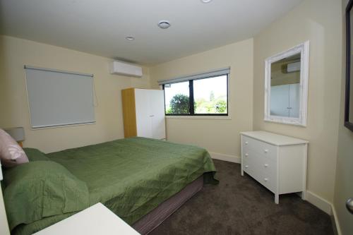 a bedroom with a green bed and a window at Riverview Retreat in Kerikeri