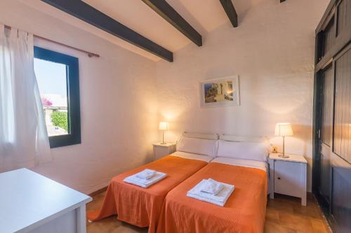 a bedroom with a bed with orange sheets and a window at Casa 6 U en Complejo Binisafua in Binisafua