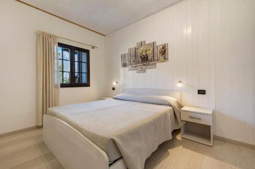 a white bedroom with a bed and a window at Casa Berthold in Ledro