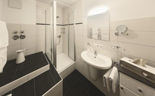 a white bathroom with a sink and a shower at Trenklehof in Simonswald
