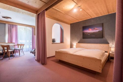 a bedroom with a bed and a dining room at Sabina Dolomites Euringer in Alpe di Siusi