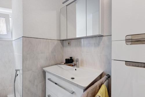 a bathroom with a white sink and white cabinets at eva Ferienwohnung in Engen