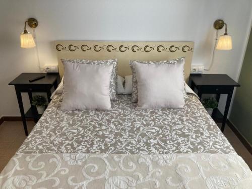 a bedroom with a bed with two tables and two pillows at Lola's Beach House in Calafell