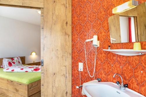 a bathroom with a sink and a bed in a room at Pension Heidelberg in Hopfgarten im Brixental