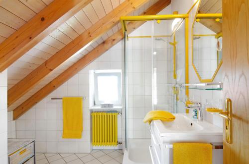 a bathroom with a sink and a shower with yellow towels at Wohlfühlplatz in Ostrach