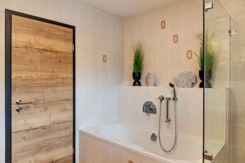 a bathroom with a tub and a shower with plants at Alpblick Apartment Alpspitze in Garmisch-Partenkirchen