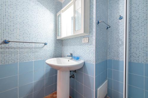 a blue tiled bathroom with a sink and a mirror at Accu is Prezzus E special 50m mare in Villasimius