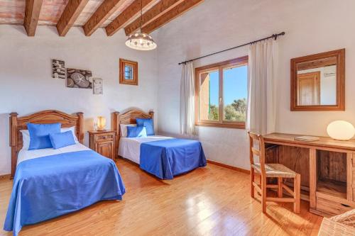 a bedroom with two beds and a desk and a window at Can Vaja in Pollença