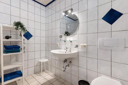 a white tiled bathroom with a sink and a mirror at Grüner Ausblick in Oberkirch