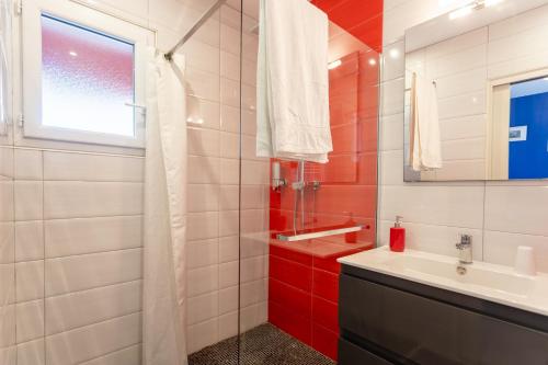 ein rot-weißes Badezimmer mit Waschbecken und Fenster in der Unterkunft Chambre - Gentiane in Aroue