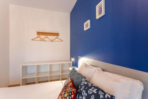 ein Schlafzimmer mit einer blauen Wand und einem Bett mit Kissen in der Unterkunft Chambre - Gentiane in Aroue